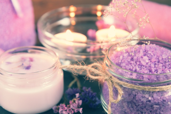 Spa products. Lavender bath salts, dry flowers, cosmetic cream, light candles and towel. Violet purple concept. Coloring and processing photo.